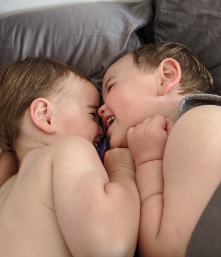 Twin brothers hugging while smiling. 