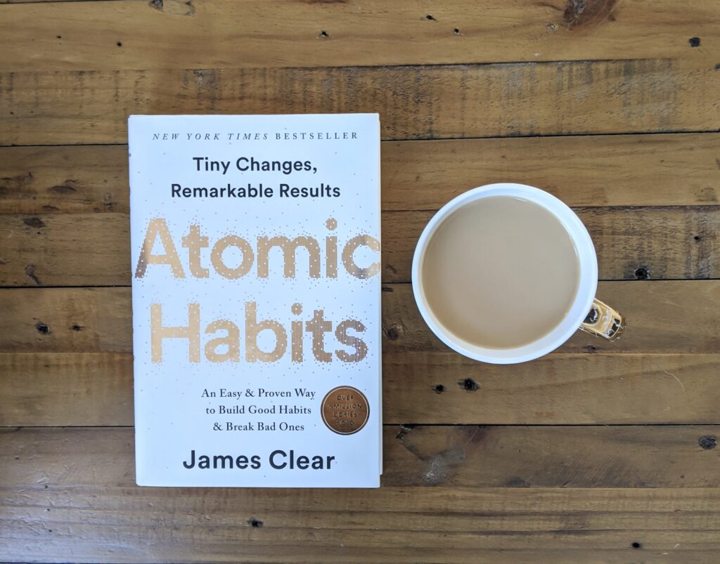 Image of the book Atomic Habits by James Clear next to a coffee cup