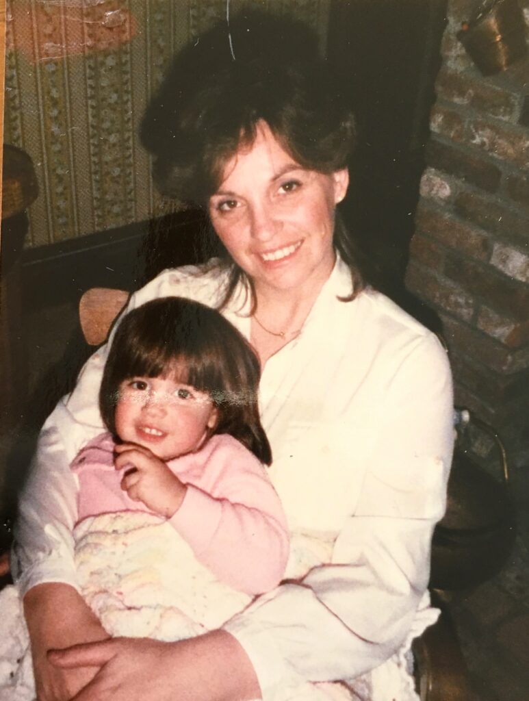 Mom with daughter on her lap with both smiling at the camera