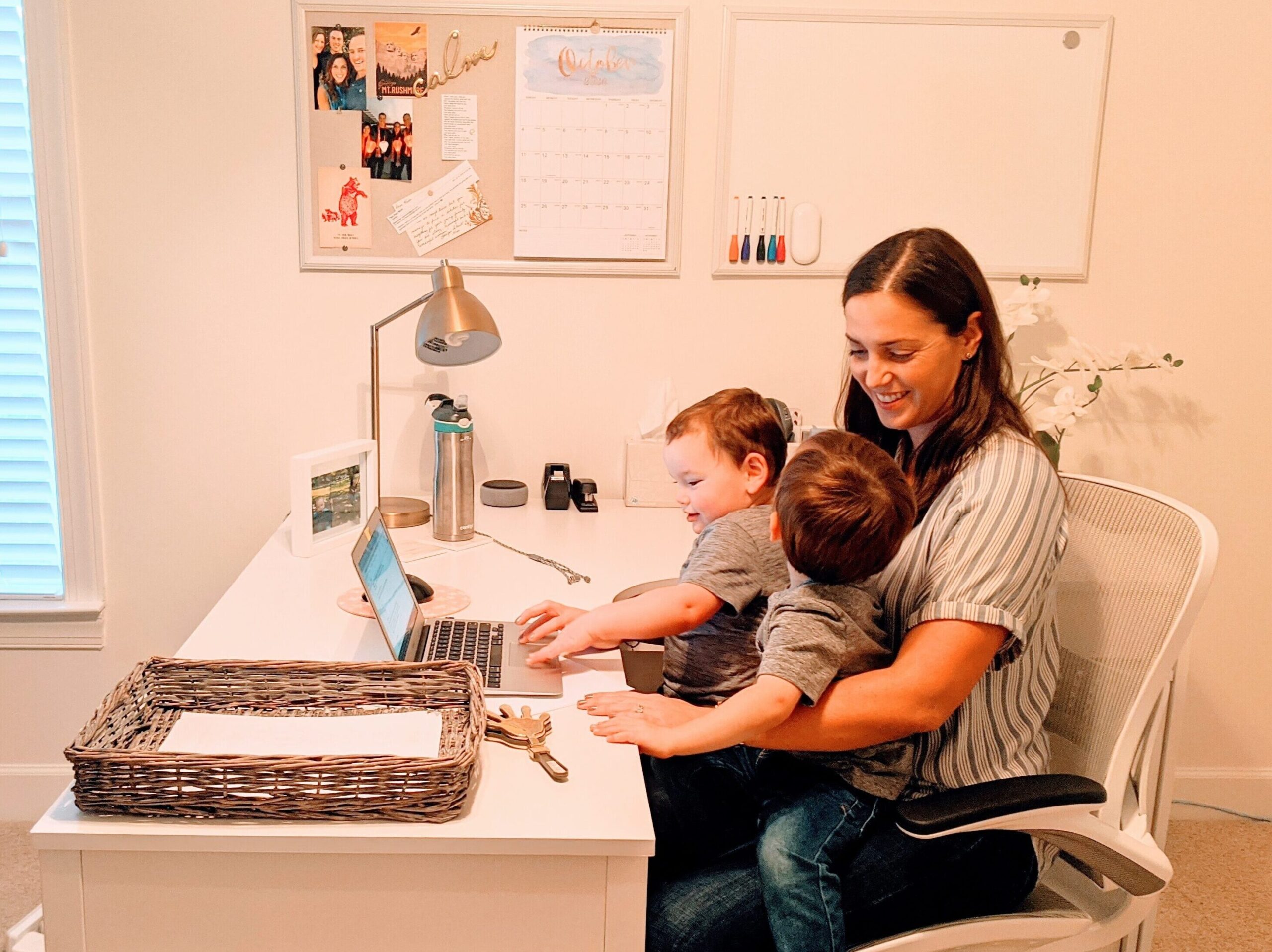 Mom sitting with twin boys at her desk in the office