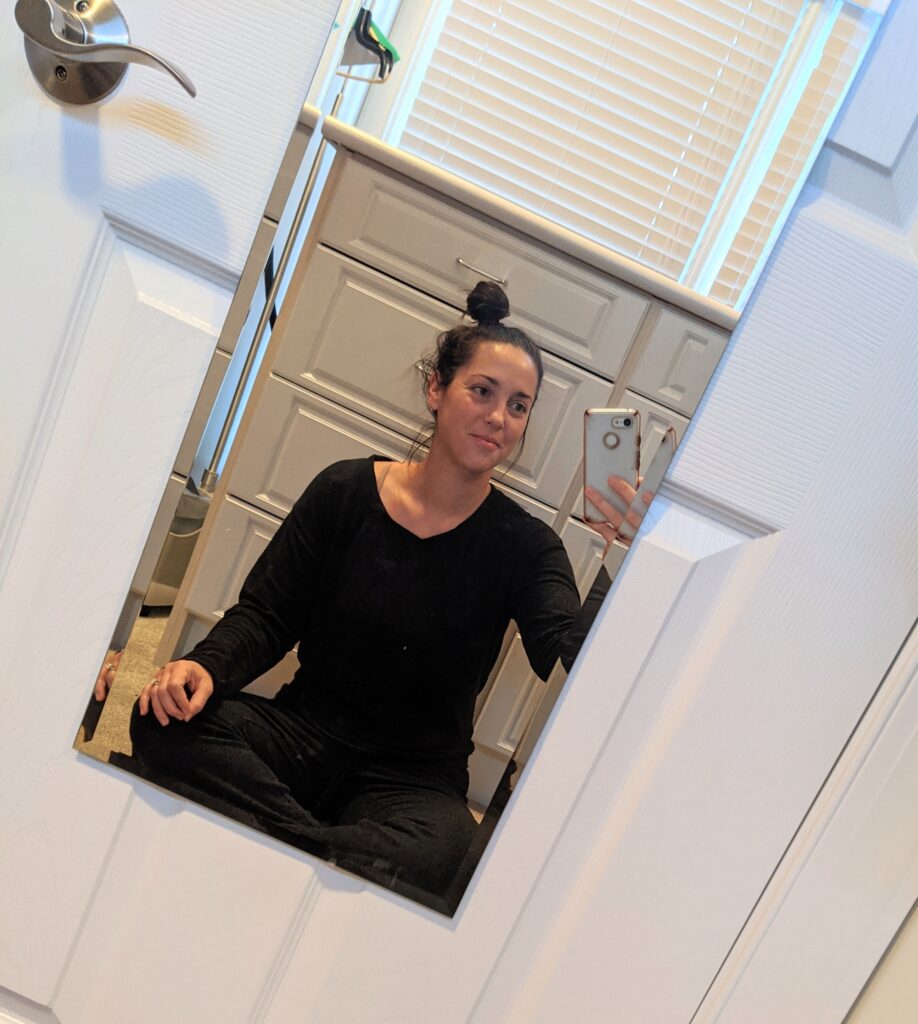 Woman taking a picture of herself meditating in a mirror 