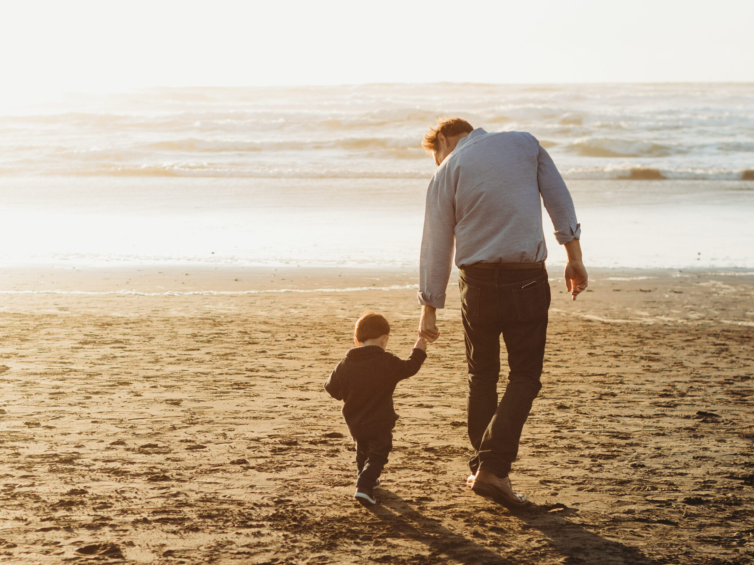 Dad and son walking on the beach 