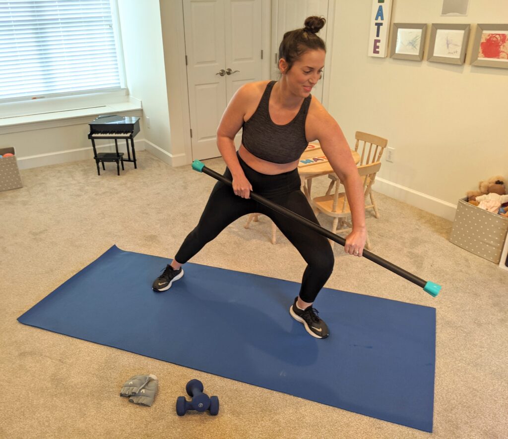 Woman working out with a weighted bar on a yoga mat